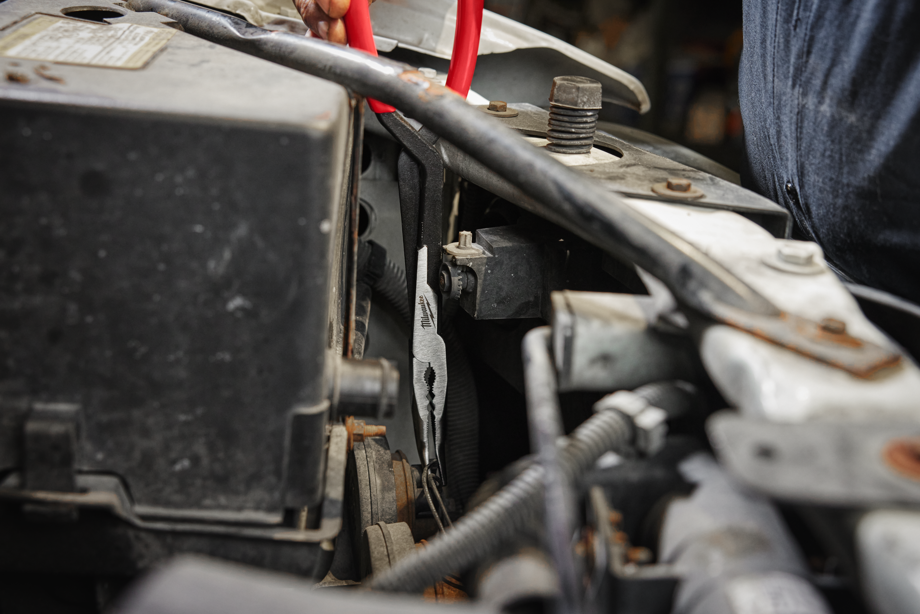 Close-up of a car electrical connections with Milwaukee long reach pliers