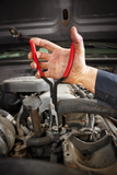 Hand using Milwaukee pliers on a car engine