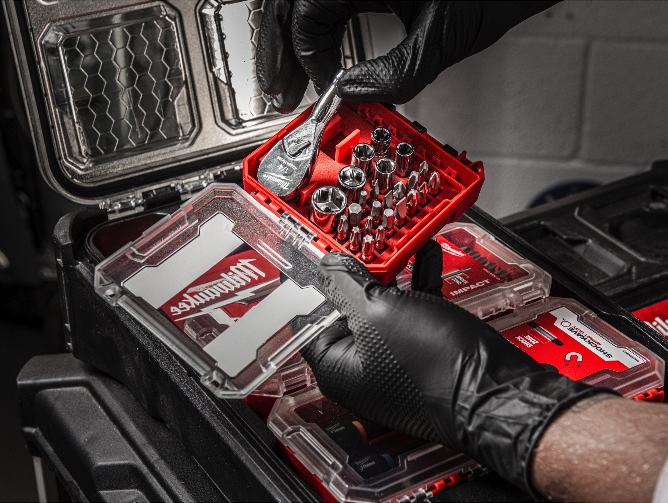 Milwaukee ¼ inch 25 piece Drive Compact Ratchet Set shown in its open packout compatible box in a work environment.