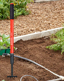 Red and black garden tool with a hose on a garden bed