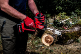 Person using a Milwaukee power tool to cut a log outdoors